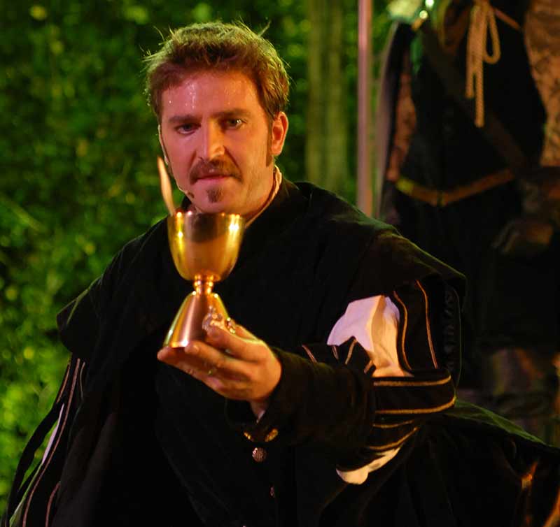 Actor vestido de época sosteniendo una copa dorada